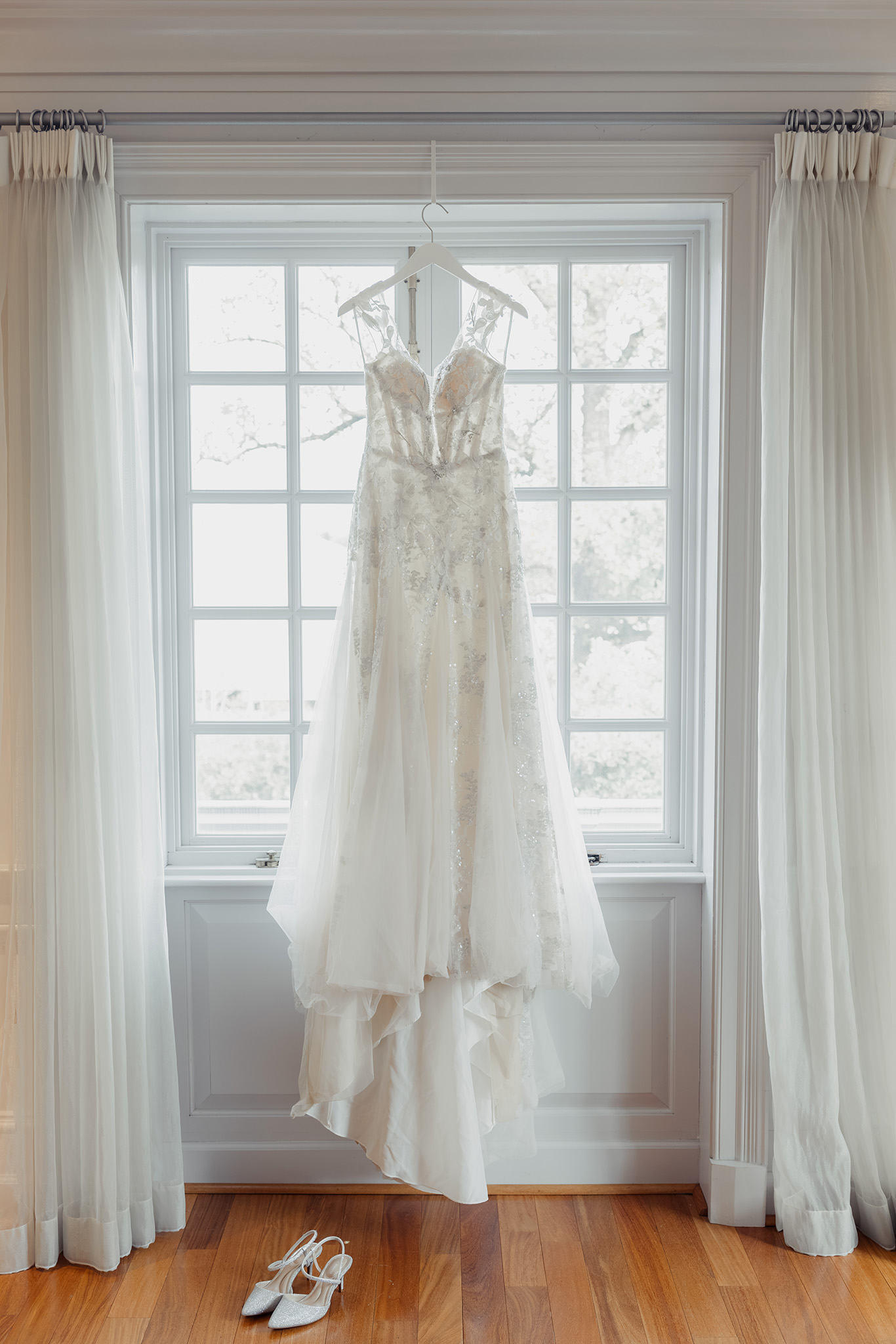 Elegant bridal gown hanging by a window in a Boston bridal suite